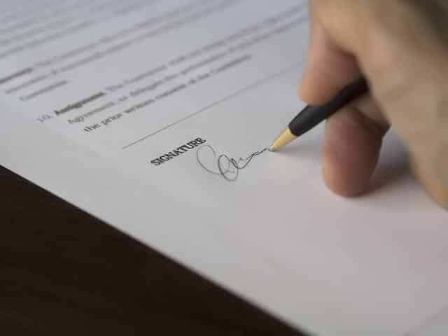 hand holding a pen signing a signature to a qualified personnel residence trust document