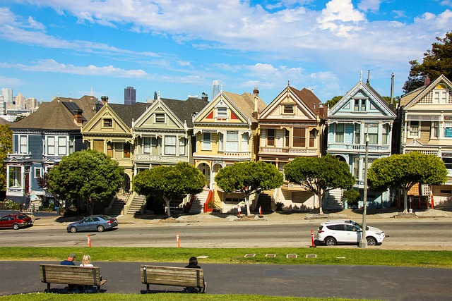 a block of multi-colored row houses on a city street next to a park 